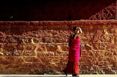 tibetan-monk-walking-along-wall-at-sunset
